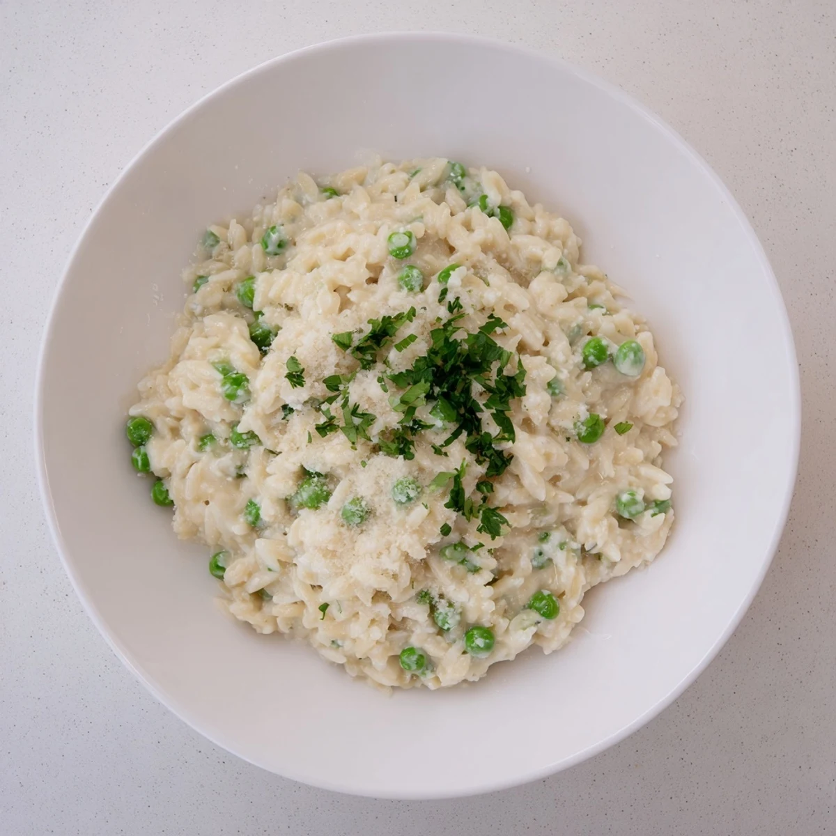 Savory Creamy Parmesan Orzo with Green Peas, garnished with parsley, perfect for a cozy dinner.