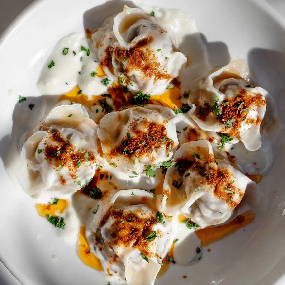 A close-up view of perfectly-formed Turkish cheesy manti, with a flavorful filling and a delicious sauce.