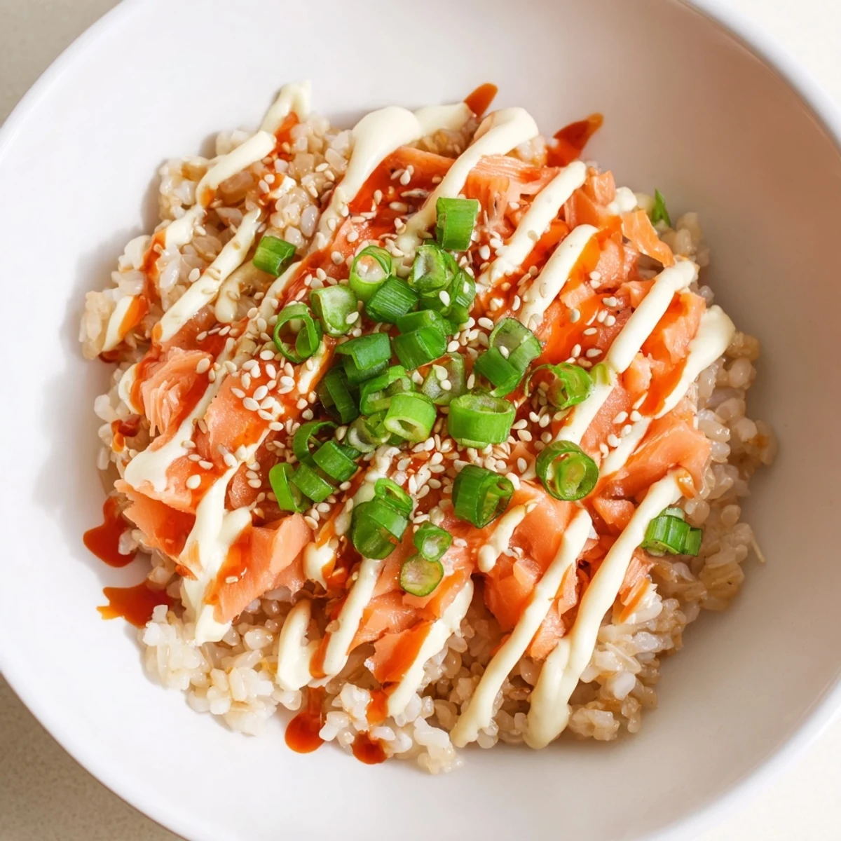 Flaky salmon and creamy avocado top the Emily Mariko Salmon Rice Bowl, served with spicy mayo and crisp seaweed.
