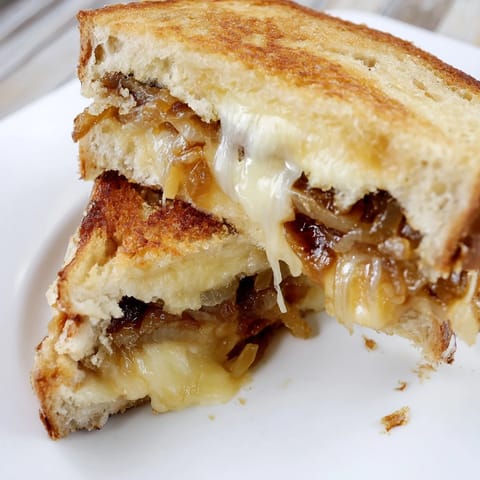 Caramelized Onion Grilled Cheese on a rustic plate, served with a creamy bowl of tomato soup for a cozy lunch.