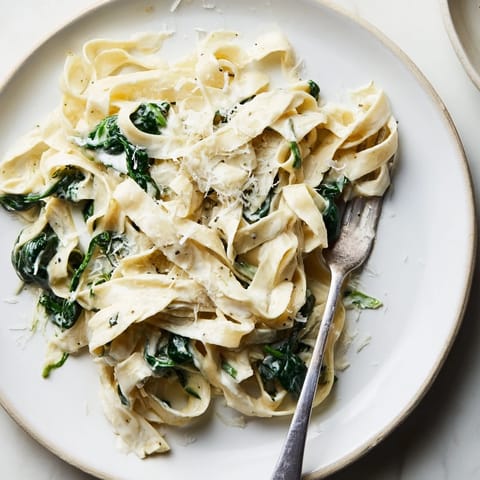 Creamy garlic spinach pasta served in a white bowl with fresh parsley and grated Parmesan on top.