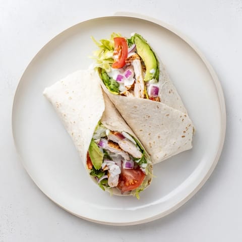 Smoky Chipotle Chicken Wrap served warm with a side of tangy Greek yogurt sauce and lime wedges on a rustic wooden table.
