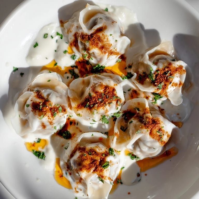 A close-up view of perfectly-formed Turkish cheesy manti, with a flavorful filling and a delicious sauce.