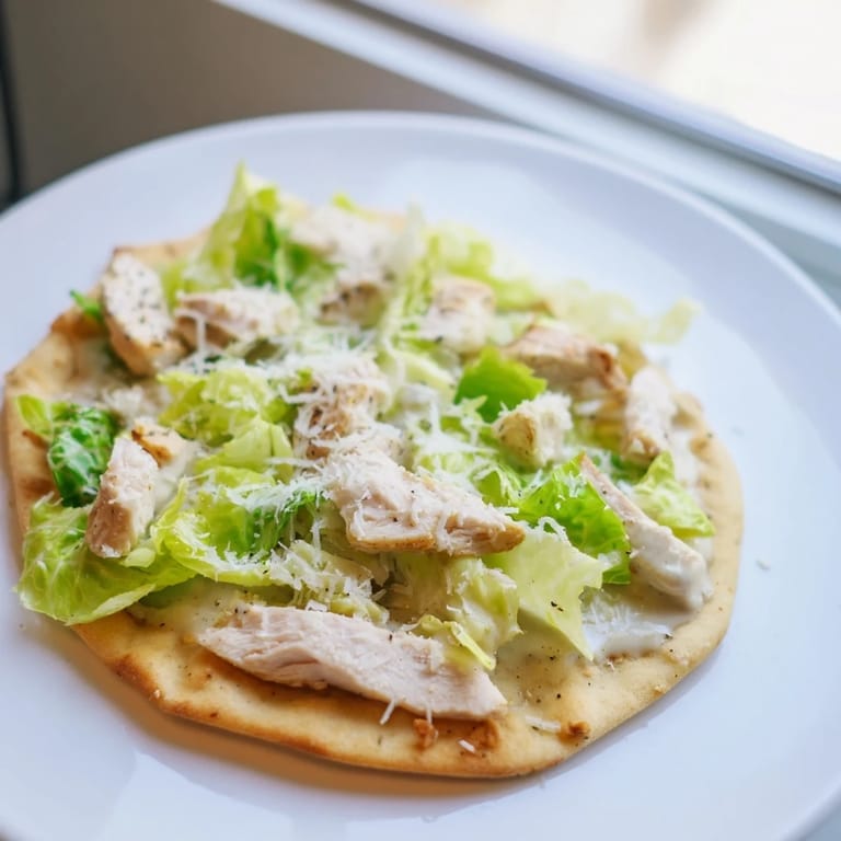 Freshly grilled Chicken Caesar Flatbread with vibrant green romaine, juicy cherry tomatoes, and a generous drizzle of tangy Caesar dressing.