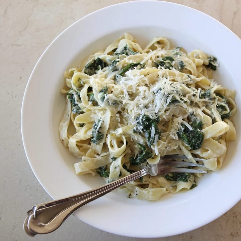 Tender spinach and garlic cloves simmering in a velvety cream sauce, tossed with perfectly cooked fettuccine.