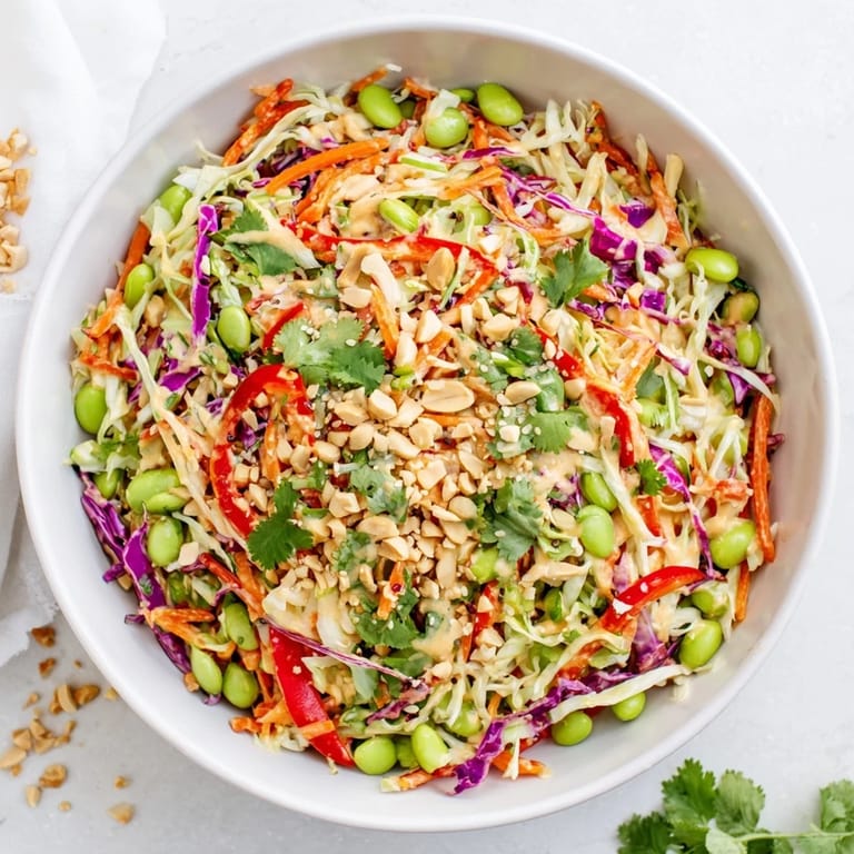 Close-up of Crunchy Thai Peanut Salad showcasing crunchy cabbage, edamame, and sesame seeds coated in tangy peanut dressing.