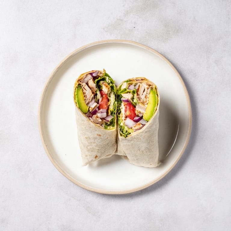 Grilled smoky chipotle chicken breast nestled in a soft flour tortilla with vibrant avocado slices and shredded lettuce for a flavorful lunch.