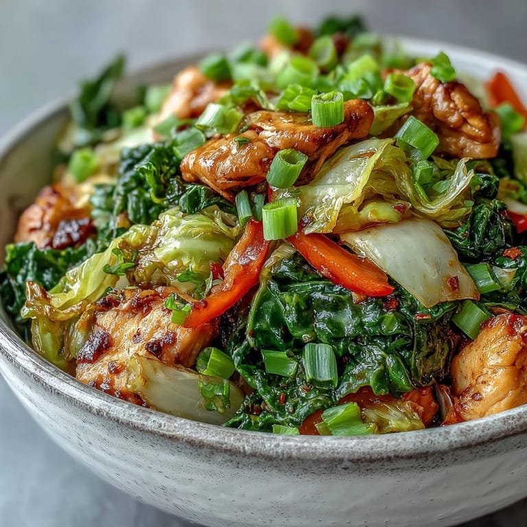 A close-up of Chicken Cabbage Stir-Fry with colorful bell peppers, carrots, and green onions, showcasing the tender chicken and vibrant, saucy vegetables in a wok.