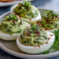 Vibrant green avocado deviled eggs with fresh herbs, perfect for spring parties and healthy snacking.