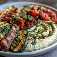 Colorful grilled veggie platter with creamy hummus, perfect for healthy summer dining and Mediterranean-inspired meals.